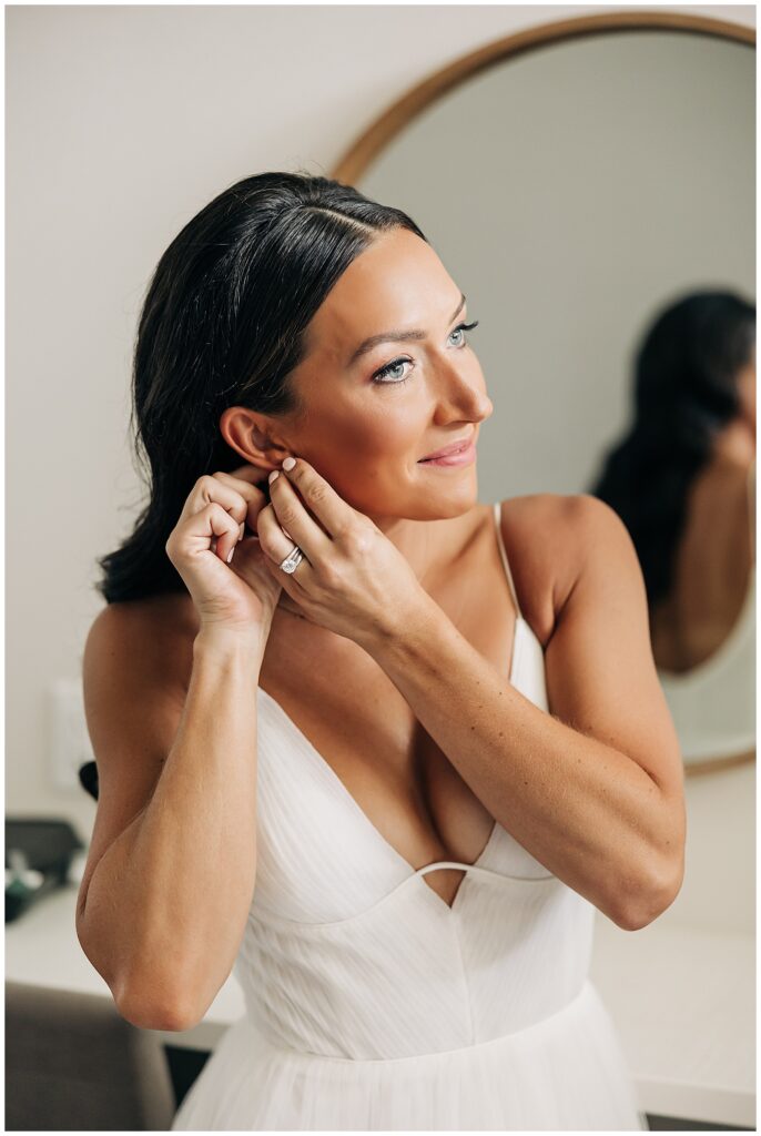 bride putting on earrings in front of mirror at Pike Lake Beach & Golf Club