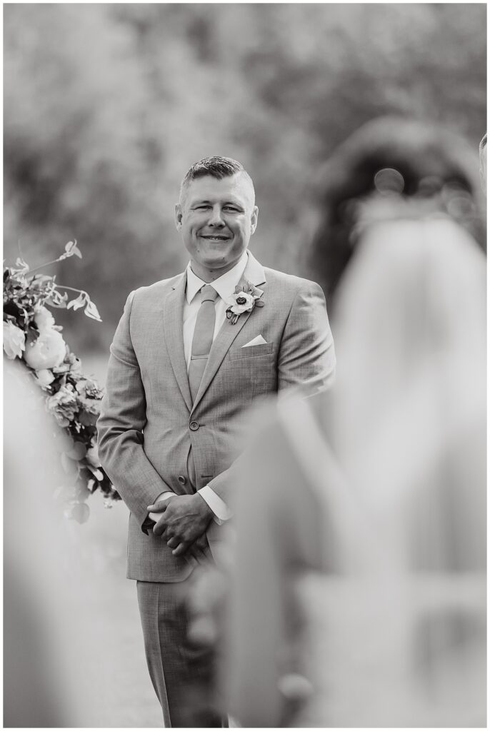 Groom looking and smiling at bride as she walks down the isle