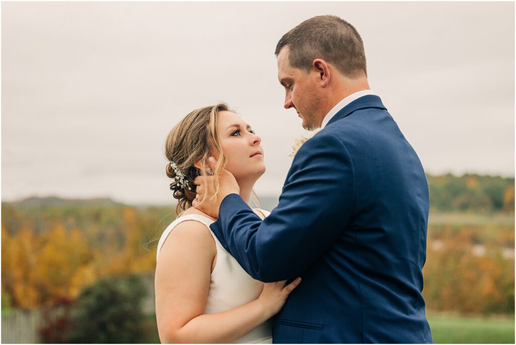 bride and groom looking at each other with fall colors in the background 